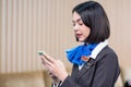 Asia attractive beautiful flight attendant/stewardess playing a smartphone in the airport lobby. Wearing in a brown uniform and Royalty Free Stock Photo