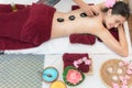 Asia beauty woman lying down on massage bed with traditional hot stones along the spine at Thai spa and wellness center, so relax Royalty Free Stock Photo