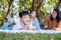 An Asia boy lying on the ground in the public garden with mother and sister under sunlight. Two hands touch his face and smile. Royalty Free Stock Photo