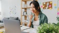 Asia businesswoman using laptop talk to colleagues about plan in video call while smart working from home at living room. Self- Royalty Free Stock Photo