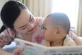 Asia Chinese Mom toddler baby boy son read book indoor home teaching early education lying on bed maternal love family Royalty Free Stock Photo