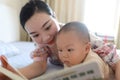 Asia Chinese Mom toddler baby boy son read book indoor home teaching early education lying on bed maternal love family Royalty Free Stock Photo