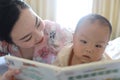 Asia Chinese Mom toddler baby boy son read book indoor home teaching early education lying on bed maternal love family Royalty Free Stock Photo