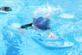 Asia cute boy wearing swimming suit and goggles used foam to practice swimming in swimming pool. Healthy kid enjoying active Royalty Free Stock Photo