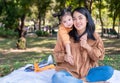 Asia daughter riding her mother back in the park. Family outdoor activity. Mom talks with the kid and there are airplane toys Royalty Free Stock Photo