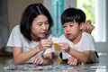 Asia family, Mother and son lying on the floor holding puzzle pieces and putting them together. Happy family during work at home. Royalty Free Stock Photo