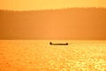 Asia fisherman on wooden boat sunset or sunrise in the river - Silhouette fisherman boat with mountain island background on the Royalty Free Stock Photo