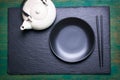 Asia food composition with chinese chopsticks, teapot and empty plate on a dark stone background Royalty Free Stock Photo