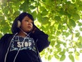 Asia girl sitting listening to music under big tree at garden park. Royalty Free Stock Photo