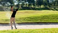 Asia Golfer man hitting out of a sand trap. The golf course is on the sand. Royalty Free Stock Photo