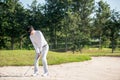 Asia Golfer man hitting out of a sand trap. The golf course is on the sand.  Hobby in holiday Royalty Free Stock Photo