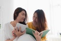 Asia lesbian lgbt couple sitting on bed reading book and use tab