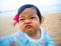 Asia little girl making funny face and red flowers in her ear. Her sitting on the beach and looking happy Royalty Free Stock Photo