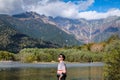 Asia man with a background of Tashiro Pond, one of Kamikochi`s most scenic spots. Tashi ike Pond is a small pond surrounded by mar