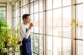 Asia man holding cup coffee and standing near window coffee break time