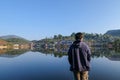Asia men traveller wearing jacket looking out at village reflection lake standing and chill out at ban rak thai Mae Hong Son