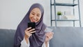 Asia muslim lady use smart phone, credit card buy and purchase e-commerce internet in living room at house. Stay at home, online Royalty Free Stock Photo