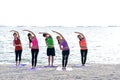 Asia people group making warrior pose on beach, fitness, sport, yoga and healthy lifestyle. Royalty Free Stock Photo