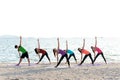 Asia people group making warrior pose on beach, fitness, sport, yoga and healthy lifestyle