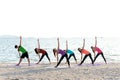 Asia people group making warrior pose on beach, fitness, sport, yoga and healthy lifestyle.