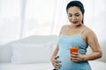 Asia Pregnant Woman Savoring Fresh Orange Juice glass sitting in bedroom with copy space Royalty Free Stock Photo