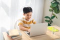 Asia preteen boy studying online on laptop with smiling and fun face at home. online education and e-learning concept Royalty Free Stock Photo