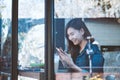 Asia teenage sitting alone using cellphone with smiling in cafe.