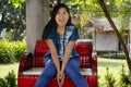 Asia thai woman travel visit and sitting on red metal bench posing for take photo in public garden park Royalty Free Stock Photo