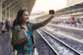 Asia woman with backpack and map, she taking photo with smartphone at railway while stand waitting train.