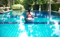 Asia woman doing yoga fitness exercise for relax and healthy beside swimming pool background