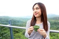 Asia woman enjoying beautiful serene morning looking at sky of mountains nature landscape scenery starting new day drinking coffee Royalty Free Stock Photo