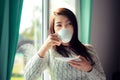 Asia woman hand holding white cup of coffee near window at the winter weather relax time, Royalty Free Stock Photo