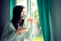 Asia woman hand holding white cup of coffee near window at the winter weather relax time, Royalty Free Stock Photo