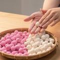 An Asia woman is making Tang yuan, yuan xiao, Chinese traditional food rice dumplings in red and white for lunar new year, winter Royalty Free Stock Photo