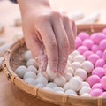 An Asia woman is making Tang yuan, yuan xiao, Chinese traditional food rice dumplings in red and white for lunar new year, winter Royalty Free Stock Photo