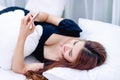 Asia woman playing the phone on the white bed in the morning Clean white room Online communication concepts