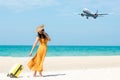 Asia women traveler holding yellow luggage walking and check in smart phone on the beach.