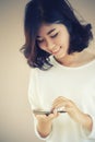 Asia Young beautiful woman writes SMS to mobile phone Royalty Free Stock Photo