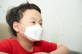 Asia young boy wear protect mask sit down on chair look away from camera