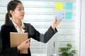 Asia young business woman plaster sticky note on the transparent glass board in the modern office and have many idea on the note Royalty Free Stock Photo