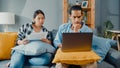 Asia young couple man and woman sit on couch serious focus on laptop computer check document paper pay bills online plan budget