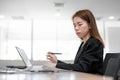 Asian accountant business woman working on desk and looking at laptop in office interior background