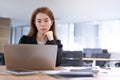 Asian accountant business woman working on desk and looking at laptop in office interior background