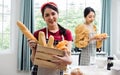 Asian adorable pretty beautiful woman smiling with happiness, holding and showing wooden basket of baked bread while staying at Royalty Free Stock Photo