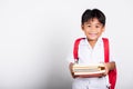 Asian adorable toddler smiling happy wearing student thai uniform red pants stand books for study ready for school