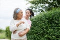 Asian adult daughter hug her senior mother in backyard garden at home . young woman embrace old mom to take care in park