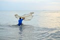 Asian adult man throwing fish net to catch fish