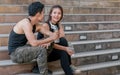 Asian adult sportive and healthy couple wearing black shirts, headphone, talking, smiling with happiness and sitting on steps