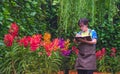 Asian adult woman in casual style is taking notes while studying the cultivation and propagation of colorful orchids in the garden