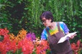Asian adult woman is taking notes while studying the cultivation and propagation of colorful orchids in ornamental garden